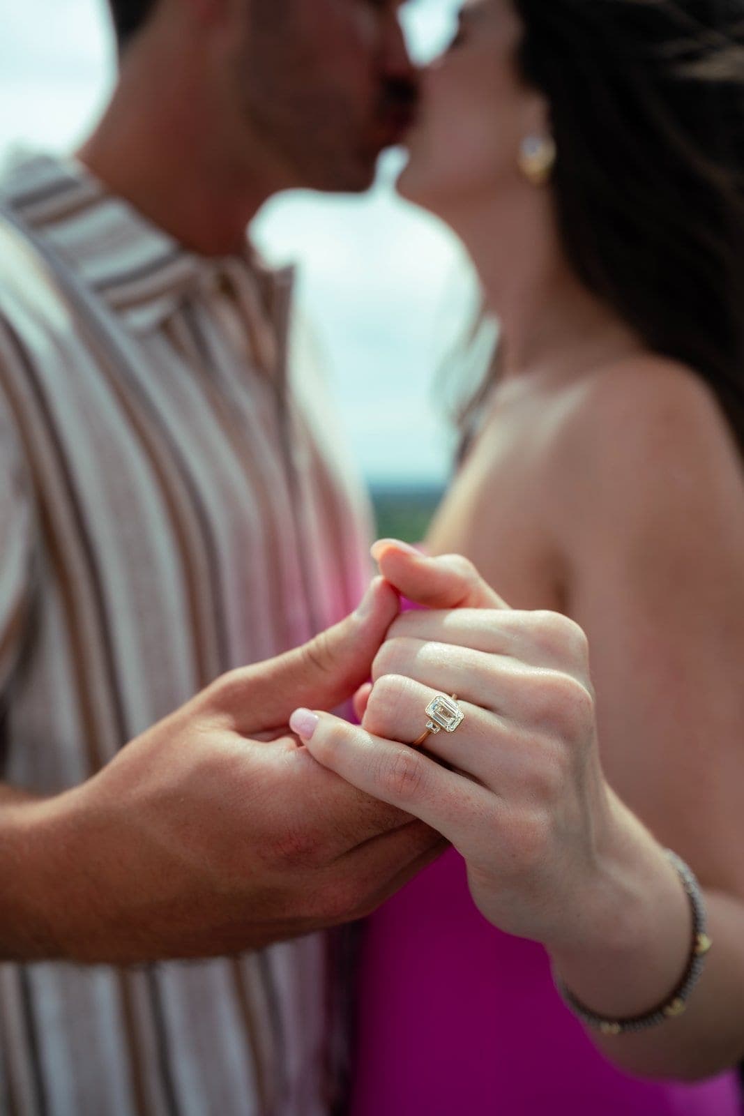 Close-up of an engagement ring as the newly engaged couple shares a kiss during an Austin proposal photography session.