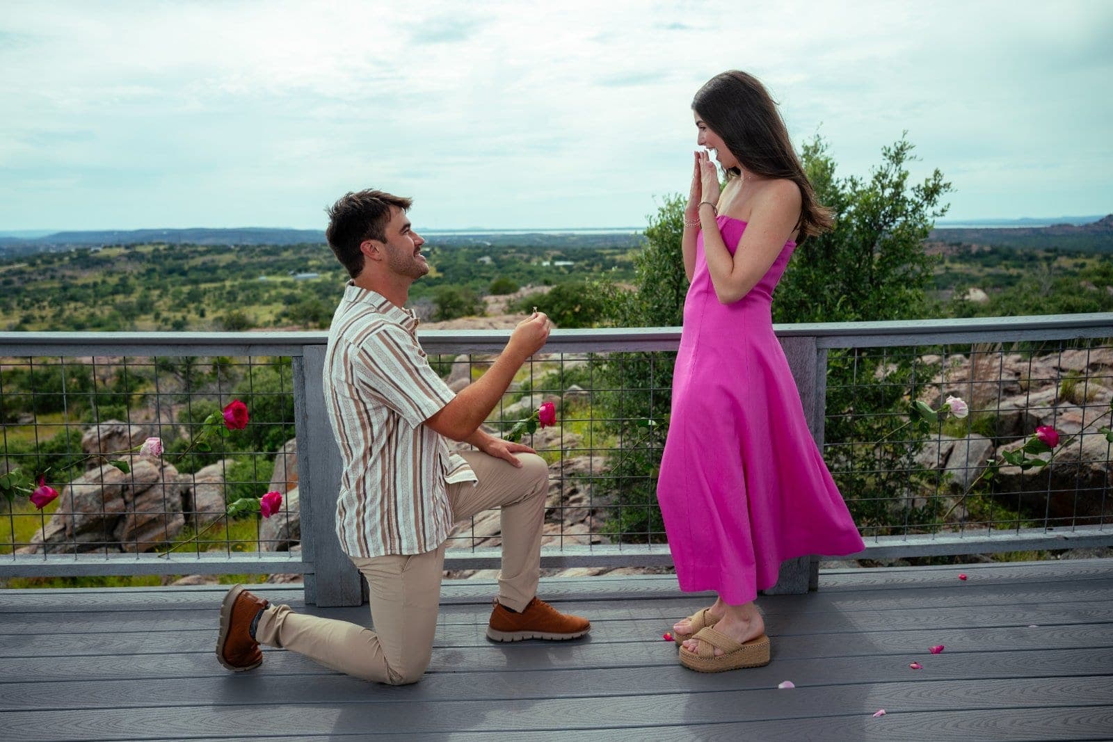 Man proposing on one knee to his partner during a surprise proposal overlooking the Texas Hill Country in Austin.