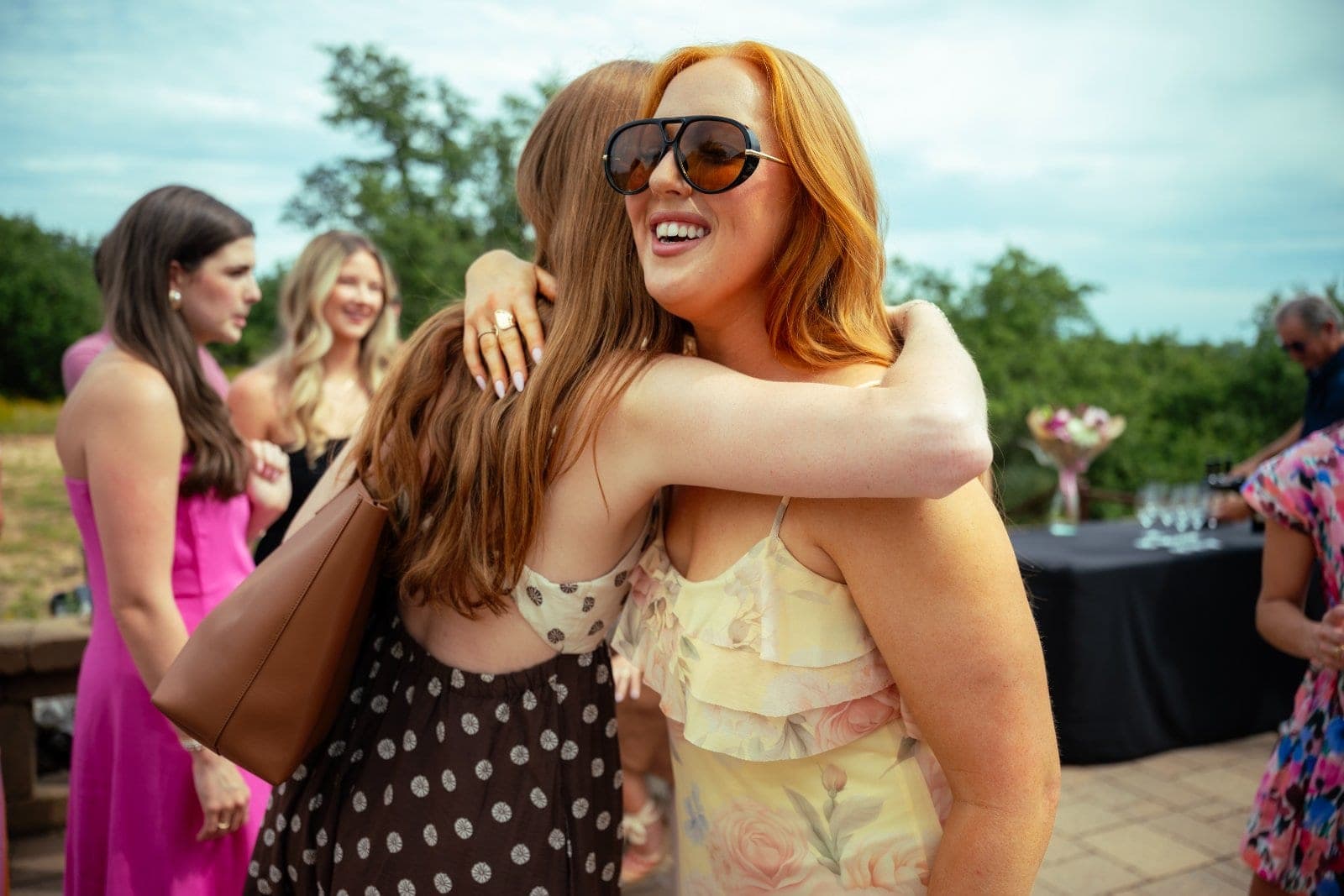 Friends embracing and celebrating after a surprise proposal during an outdoor gathering in Austin, Texas.