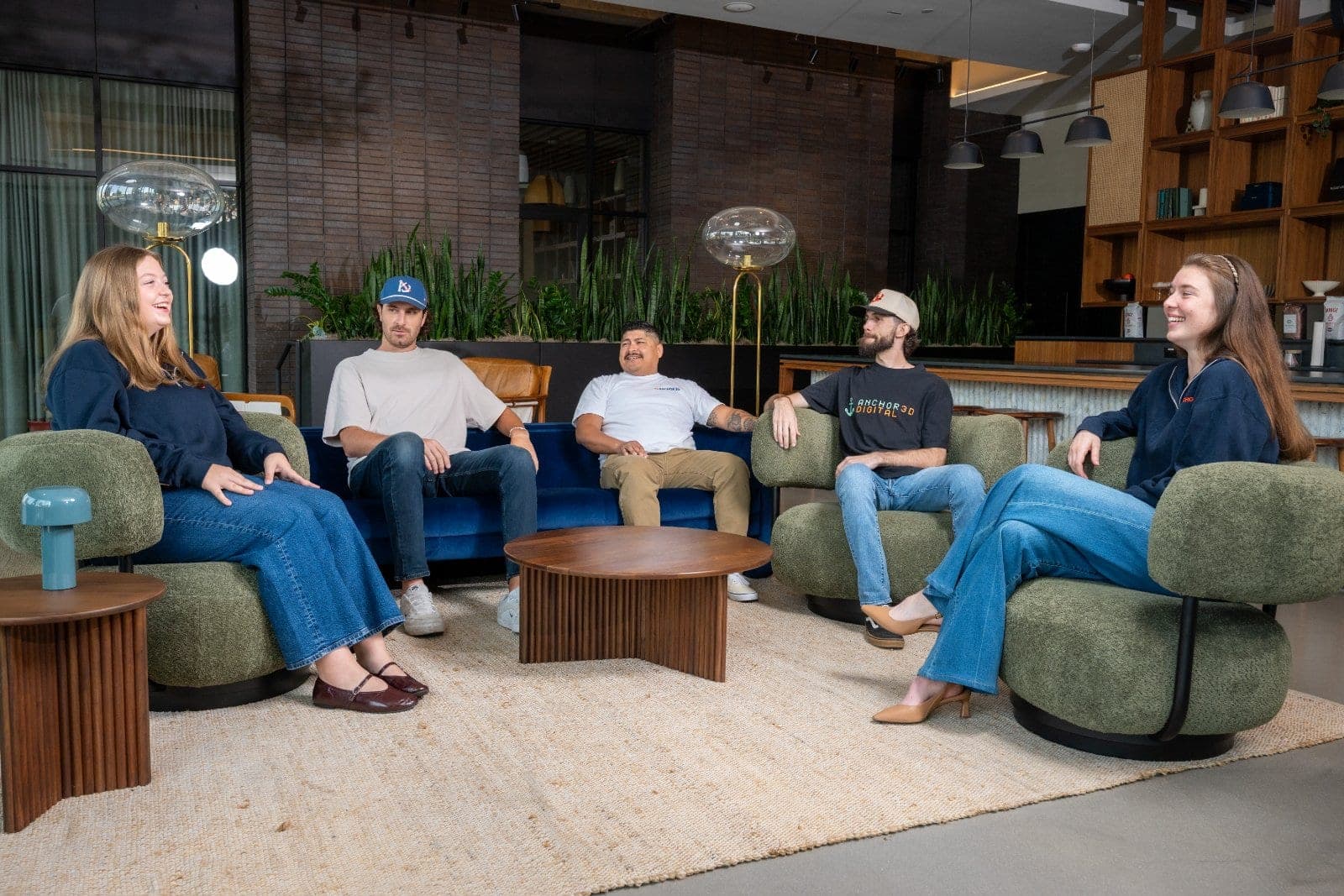 Group of coworkers seated together in a modern office lounge during a casual team conversation.
