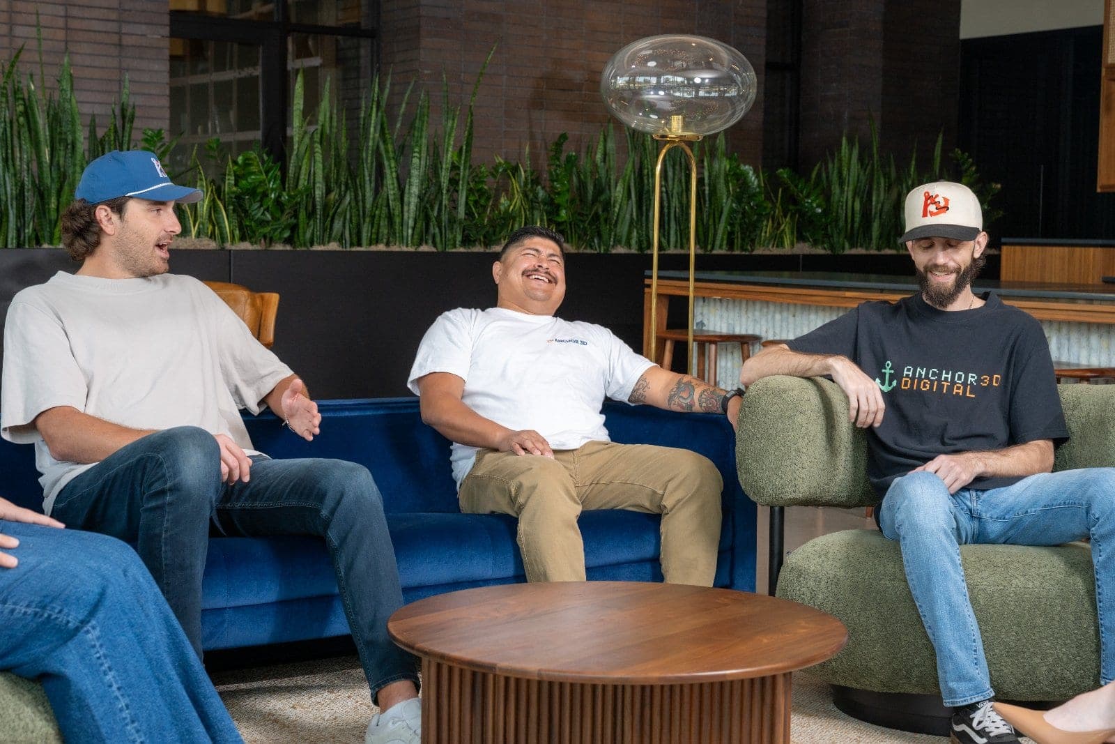 Coworkers smiling and talking together during a candid team meeting in a modern office lounge.