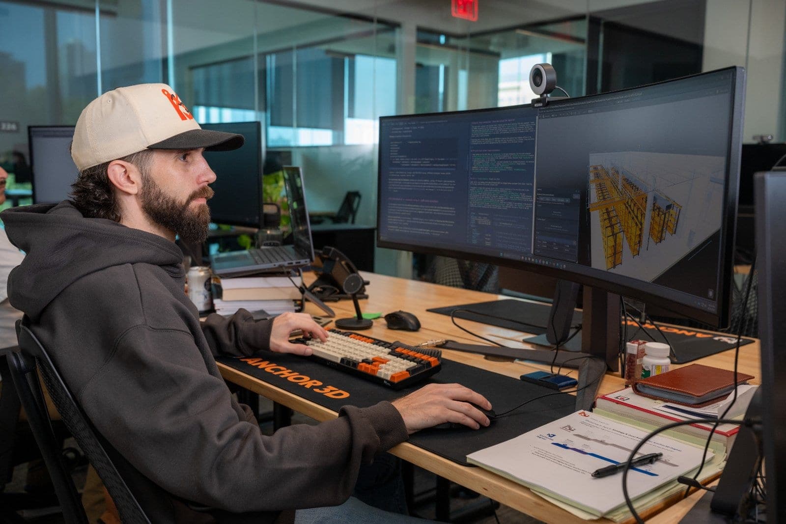 Employee working at a computer workstation with multiple monitors during a candid office photography session.