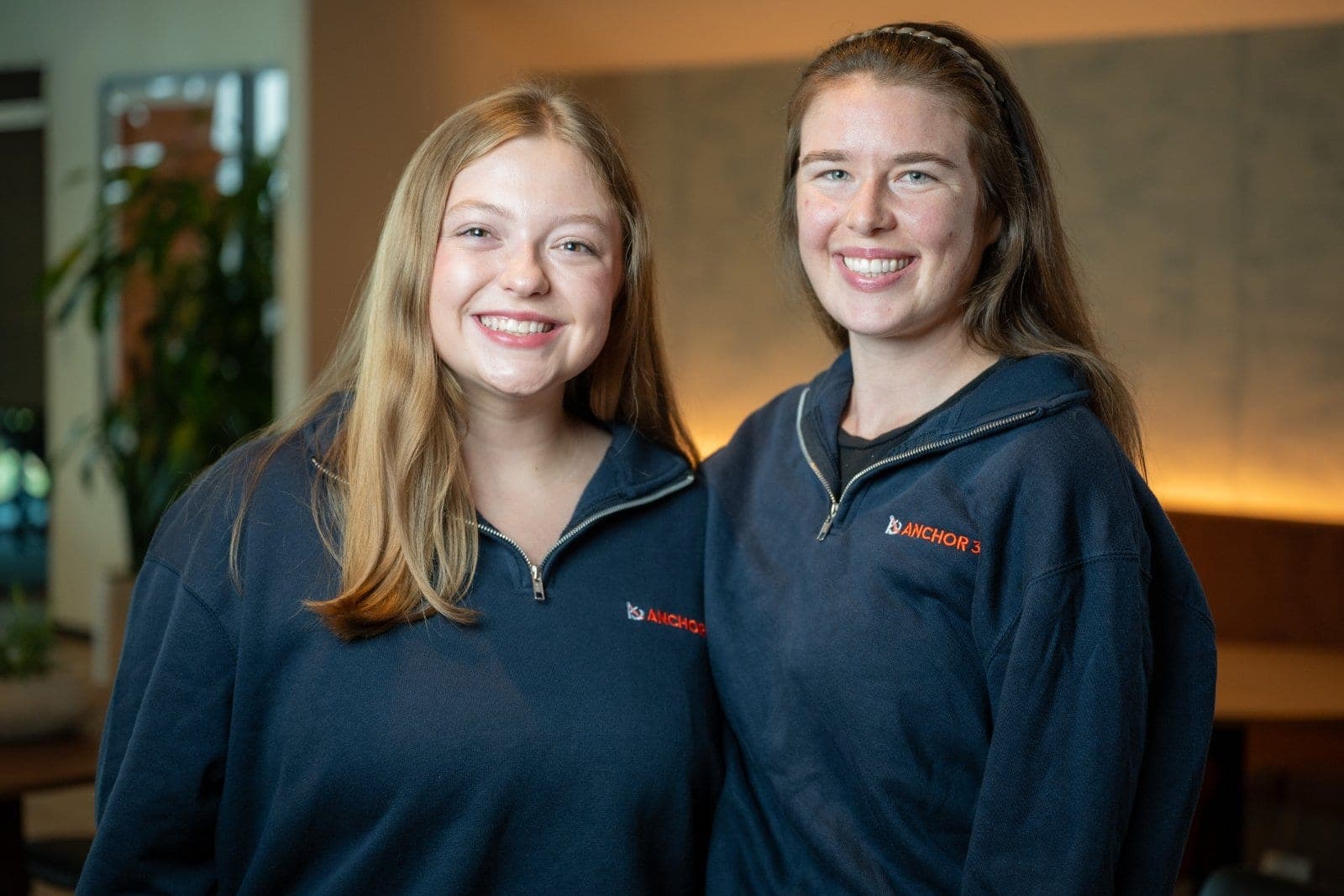 Two smiling team members standing together for a professional workplace portrait indoors.