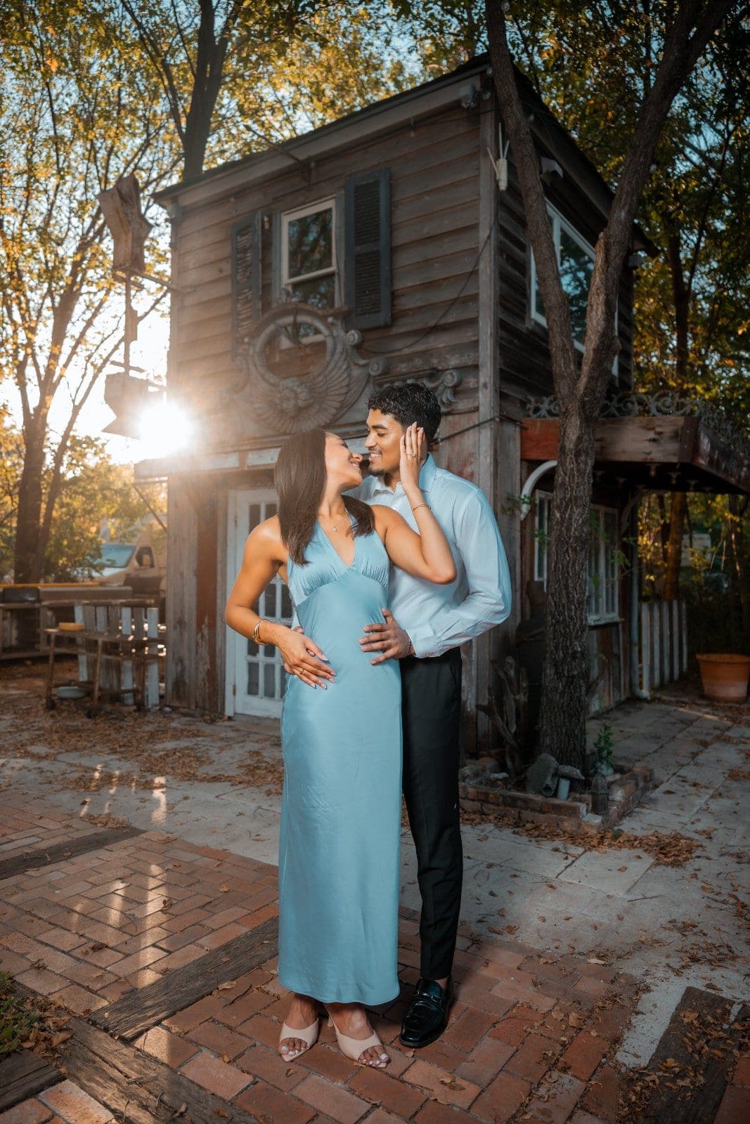 Engaged couple sharing a kiss outdoors in warm evening sunlight after their proposal in Austin, Texas.