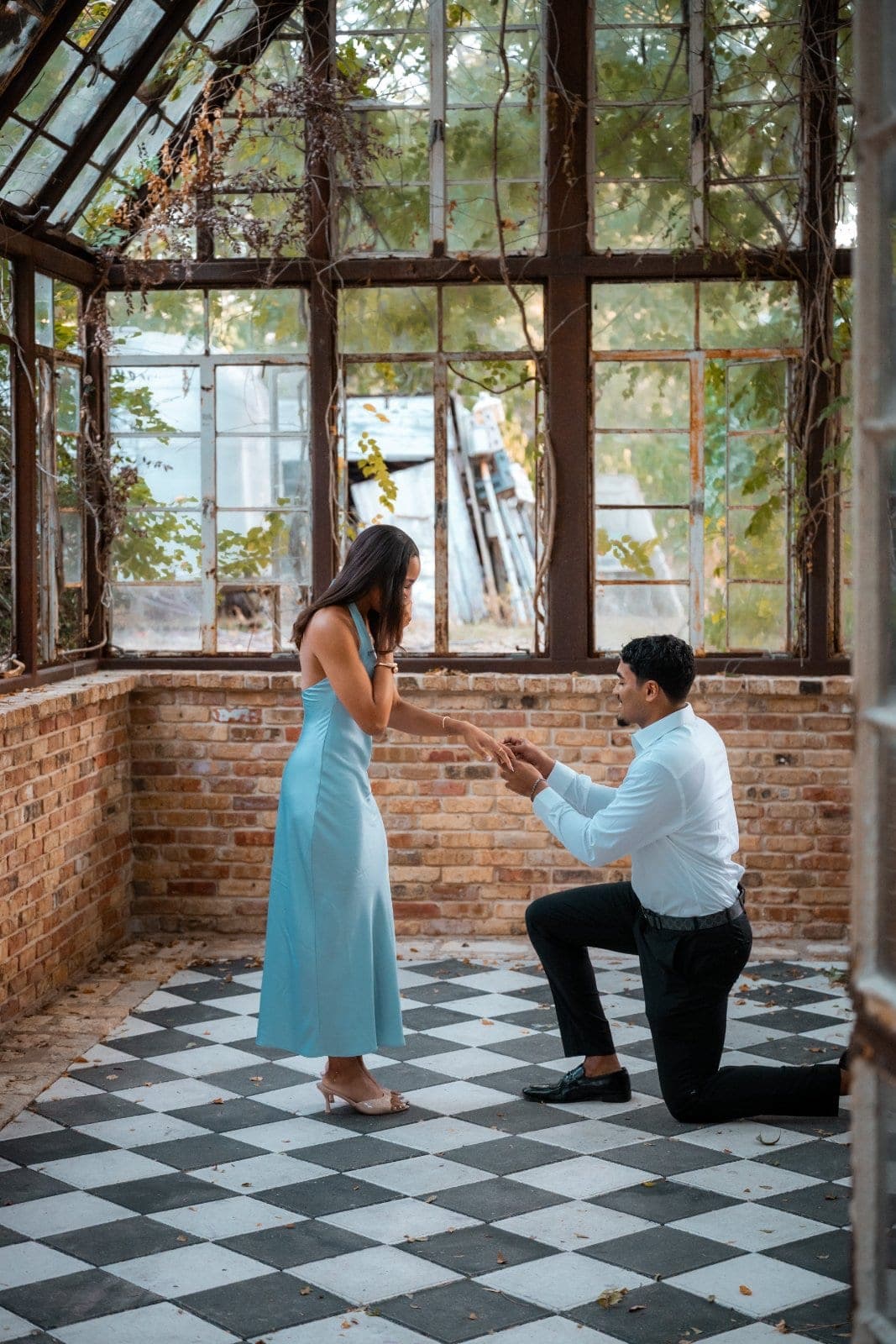 Man down on one knee proposing to his partner inside a rustic greenhouse in Austin, Texas.