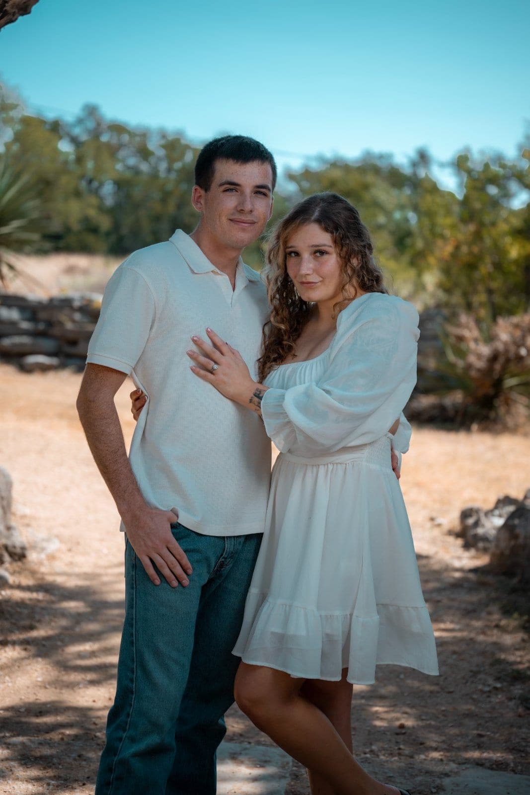 Newly engaged couple posing outdoors with the engagement ring visible during their proposal photography session in Burnet, Texas.