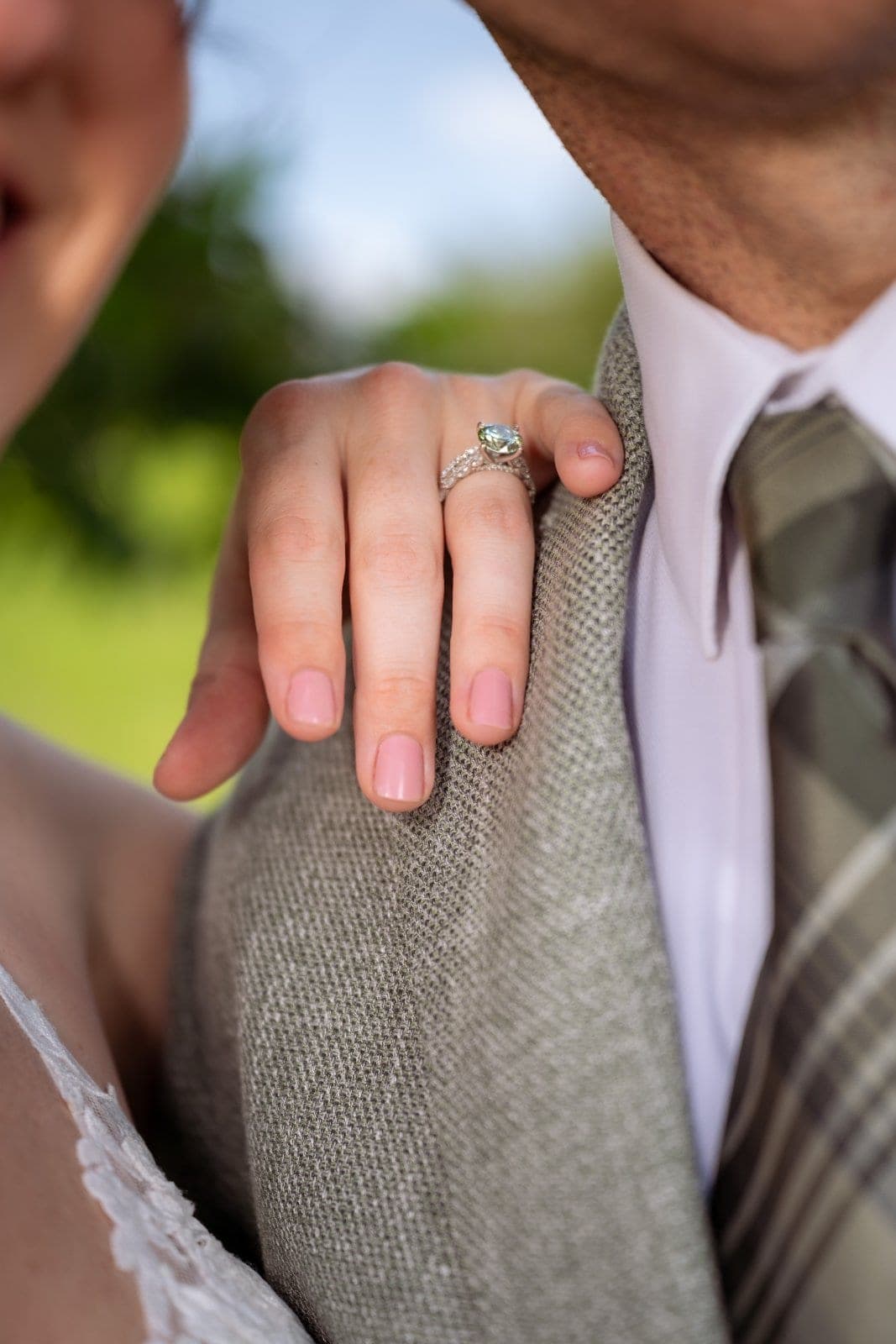 Close-up of the bride’s hand and wedding ring resting on the groom’s wedding jacket.